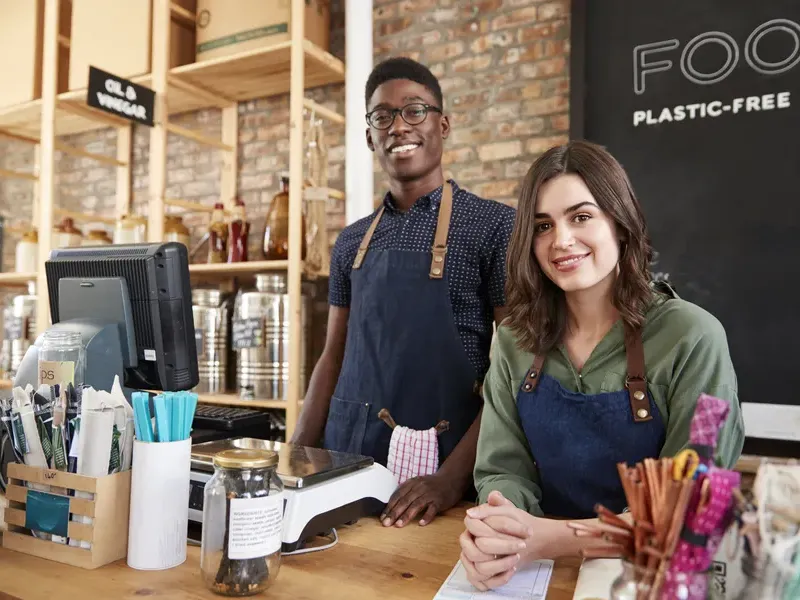 Smiling shop owners at the counter highlight success after listing their store in our business directory for local customers